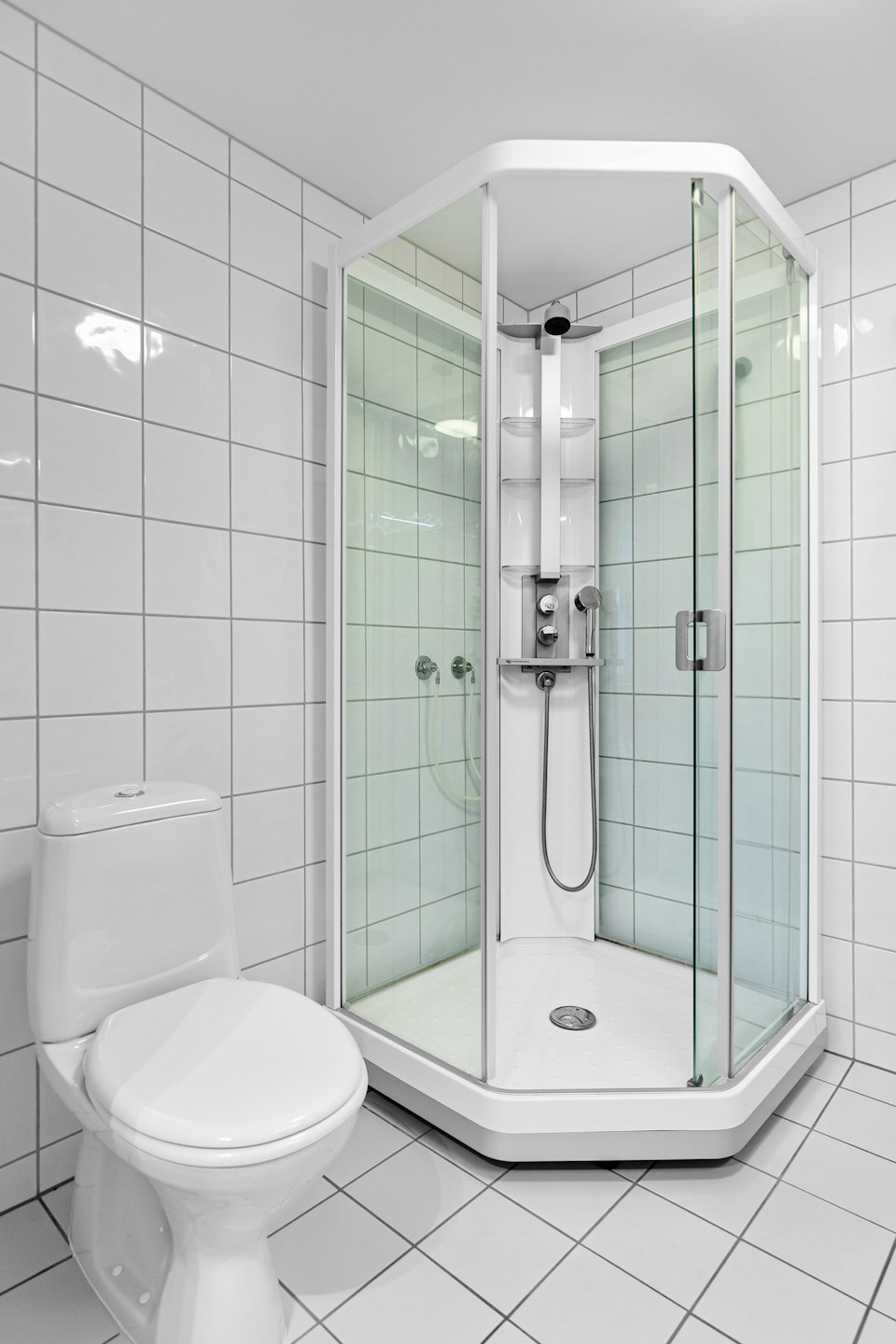 Modern white toilet and glass shower in a tiled bathroom.